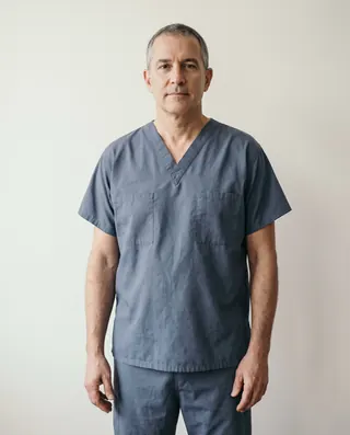 Dr. Paul Lindqvist in surgical scrubs, standing against a plain wall